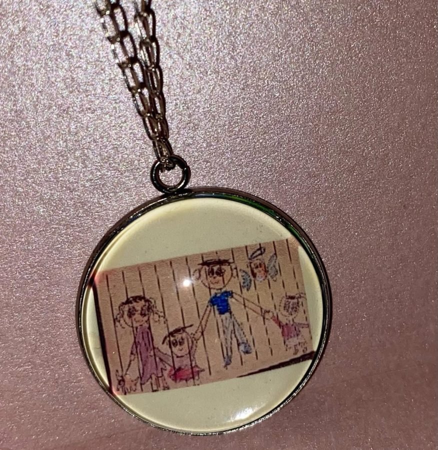 Dije de cadena oscura con el dibujo a crayón de una familia completa.